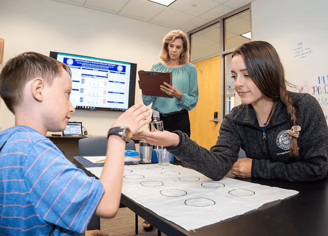 Occupational Therapist helping a child with a hand therapy exercise.